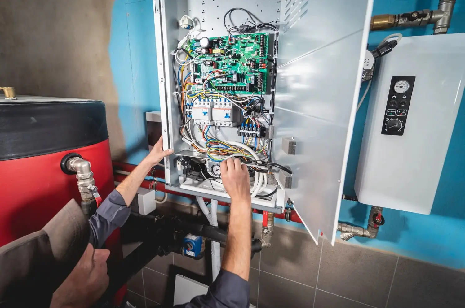 Technician working on a complex boiler control panel with circuit boards.