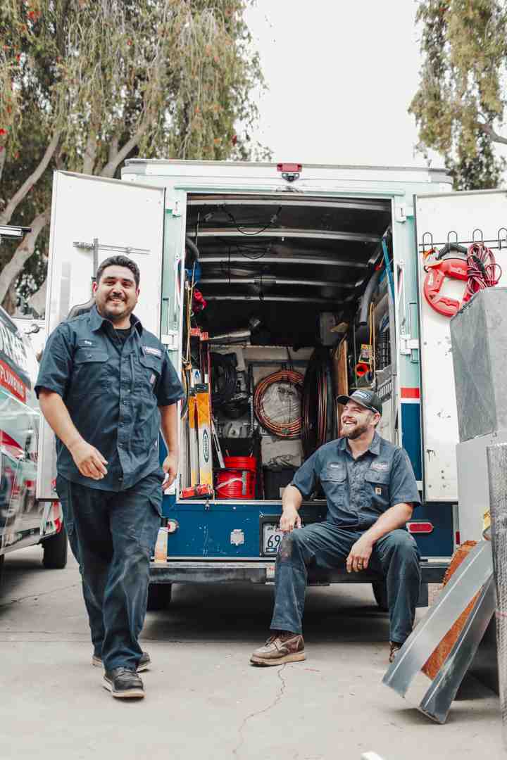 friendly uniformed plumber next to a service van - sewer replacement camarillo ca