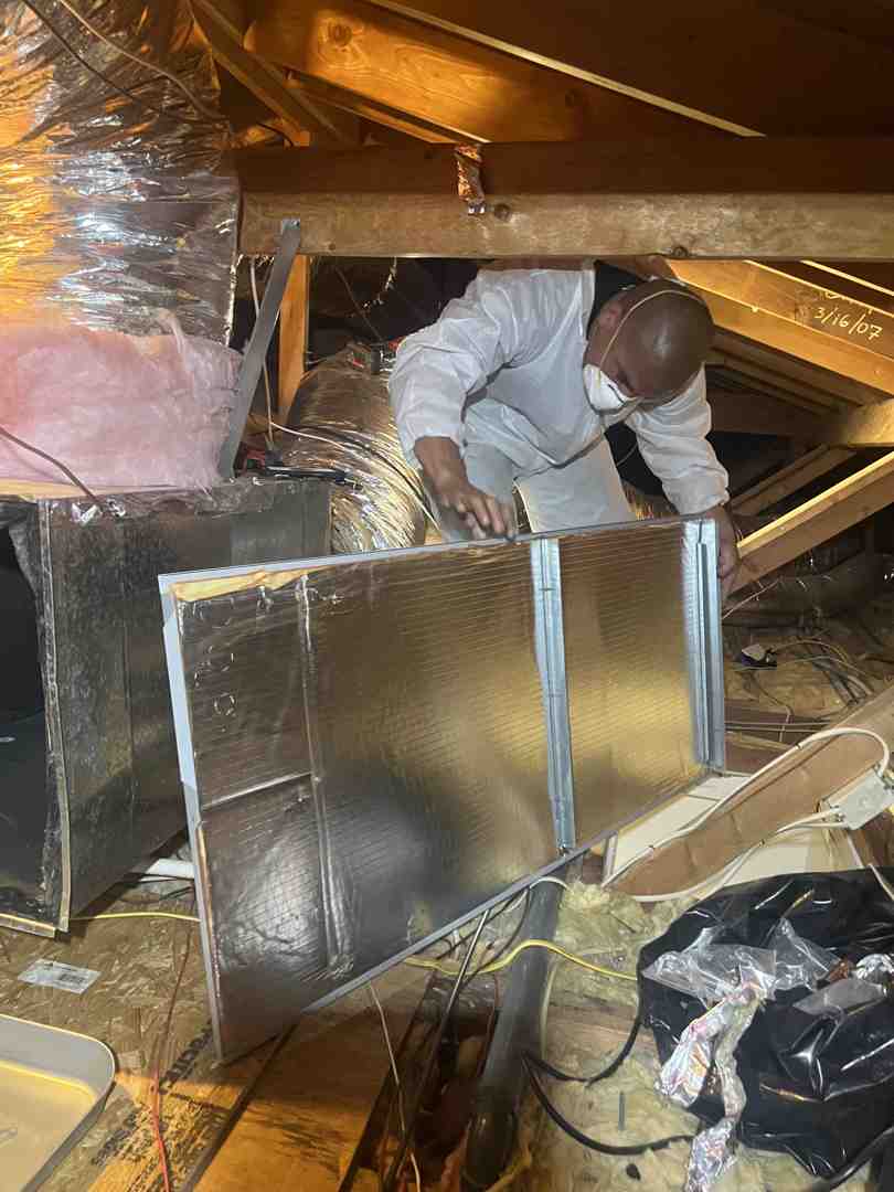 A technician carefully inspecting ductwork in an attic, ensuring proper sealing and insulation - hvac installation calabasas ca