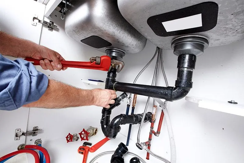 Plumber repairing double kitchen sink pipes.