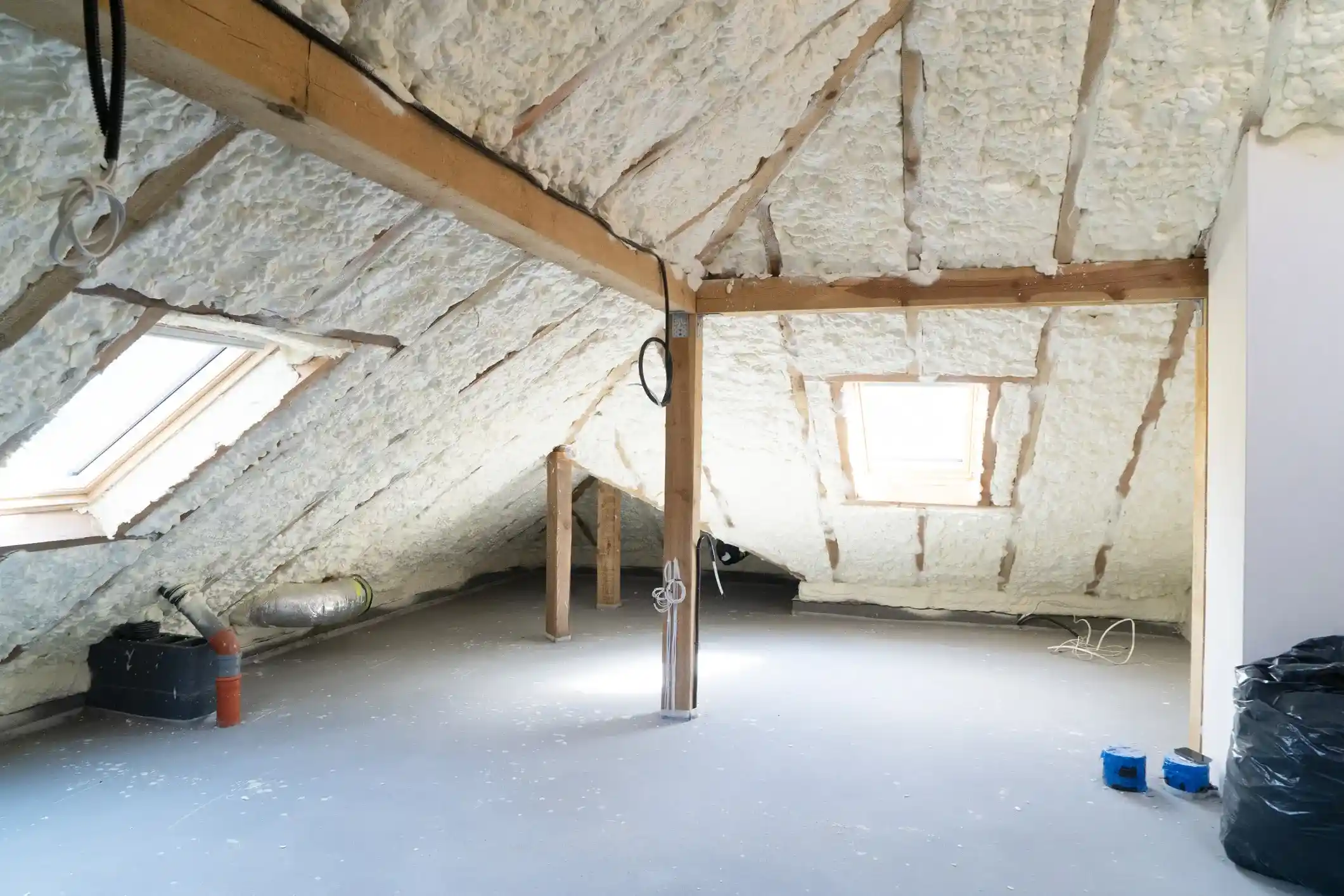 A finished attic space with skylights and walls covered in a white, spray-on foam insulation.