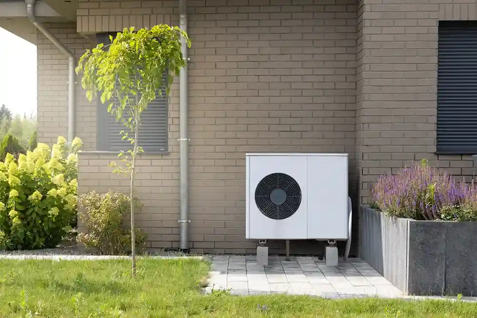 Front view of a compact white air source heat pump unit installed on concrete blocks outside a home.