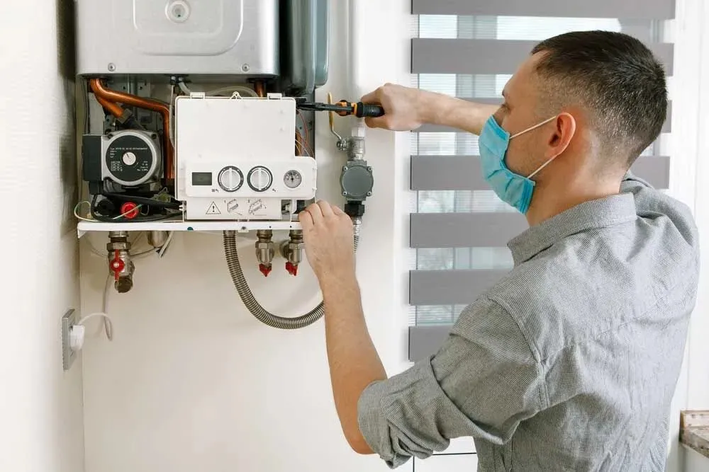 Plumber installing a wall-mounted water heater.