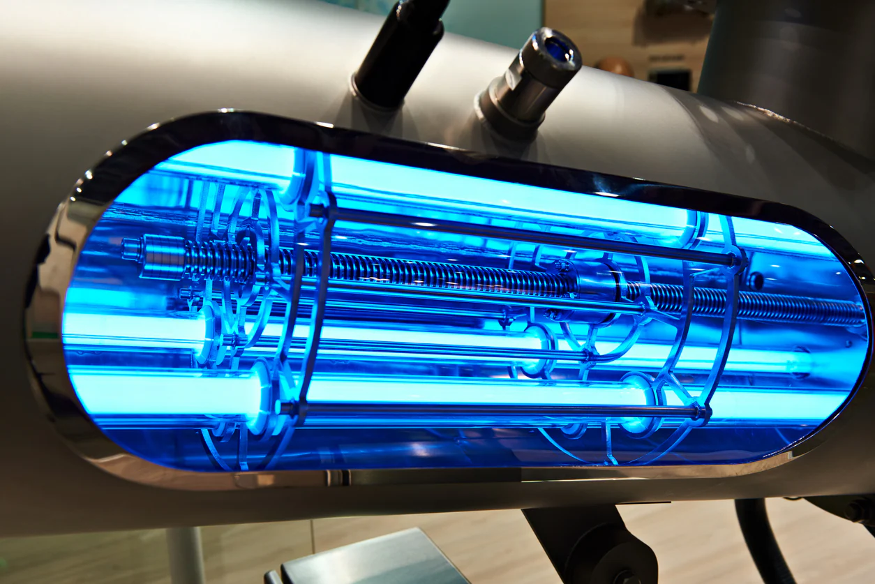 An image of a UV air purifier shows two blue, glowing tubes extending from a black rectangular base, designed to be installed in a duct