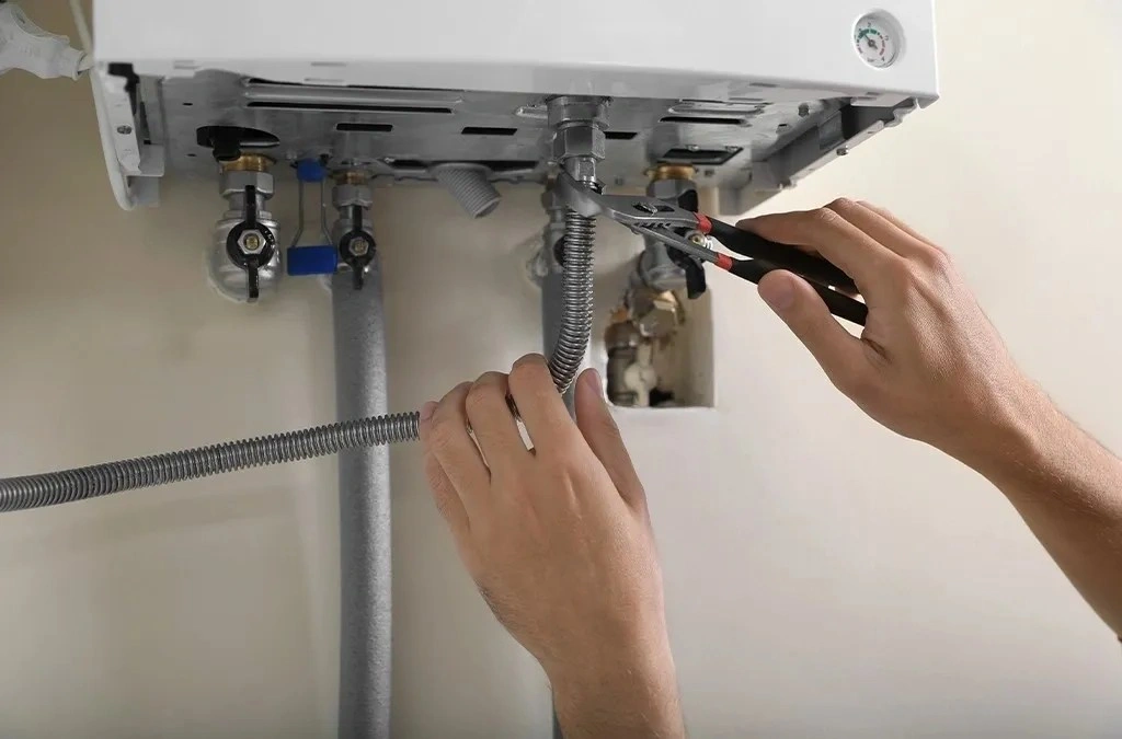 Hands using pliers on heater pipes.