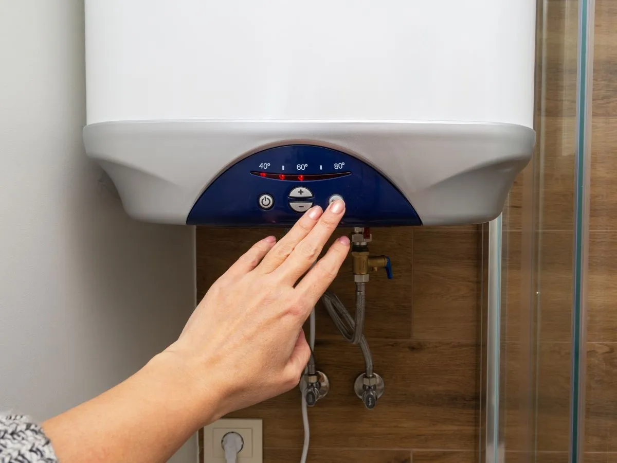 Person adjusting temperature on water heater.