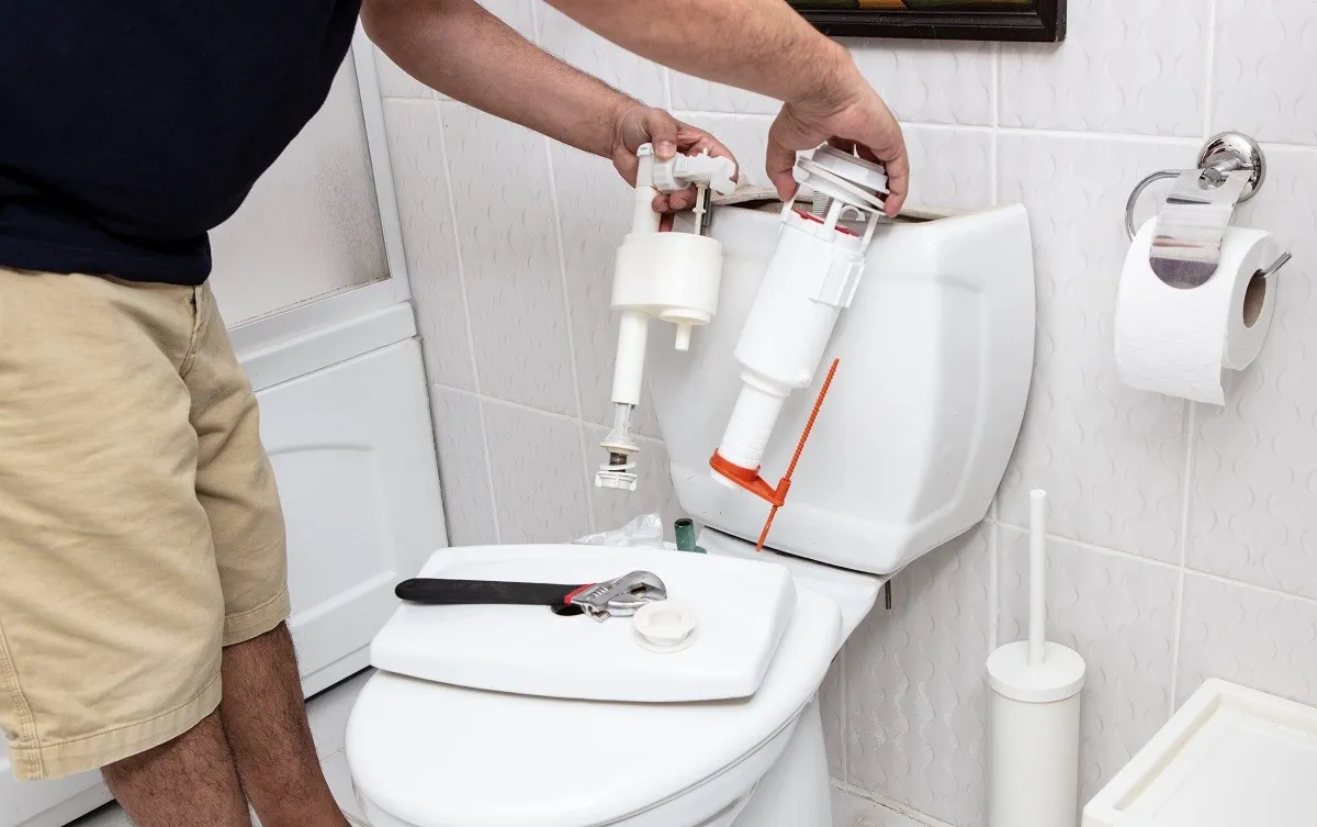 Man replacing parts in toilet tank.