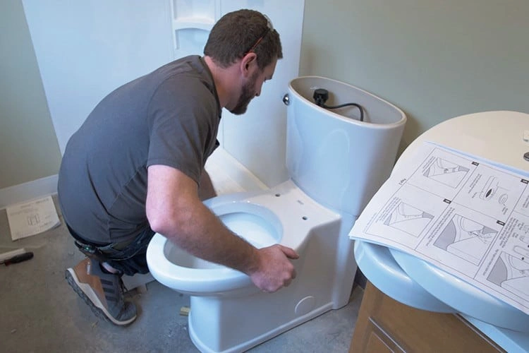 Man positioning toilet bowl on floor.