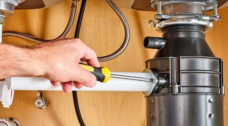 Hand tightening a garbage disposal pipe.