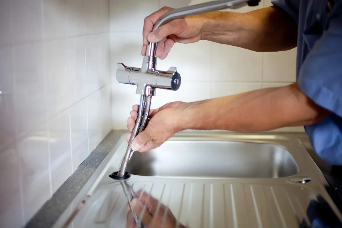 Hands inserting new faucet into sink.