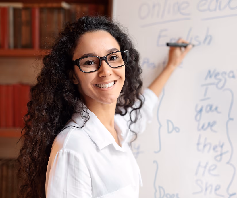 Teacher writing in front of a whiteboard.