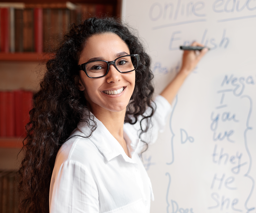 Teacher writing in front of a whiteboard.