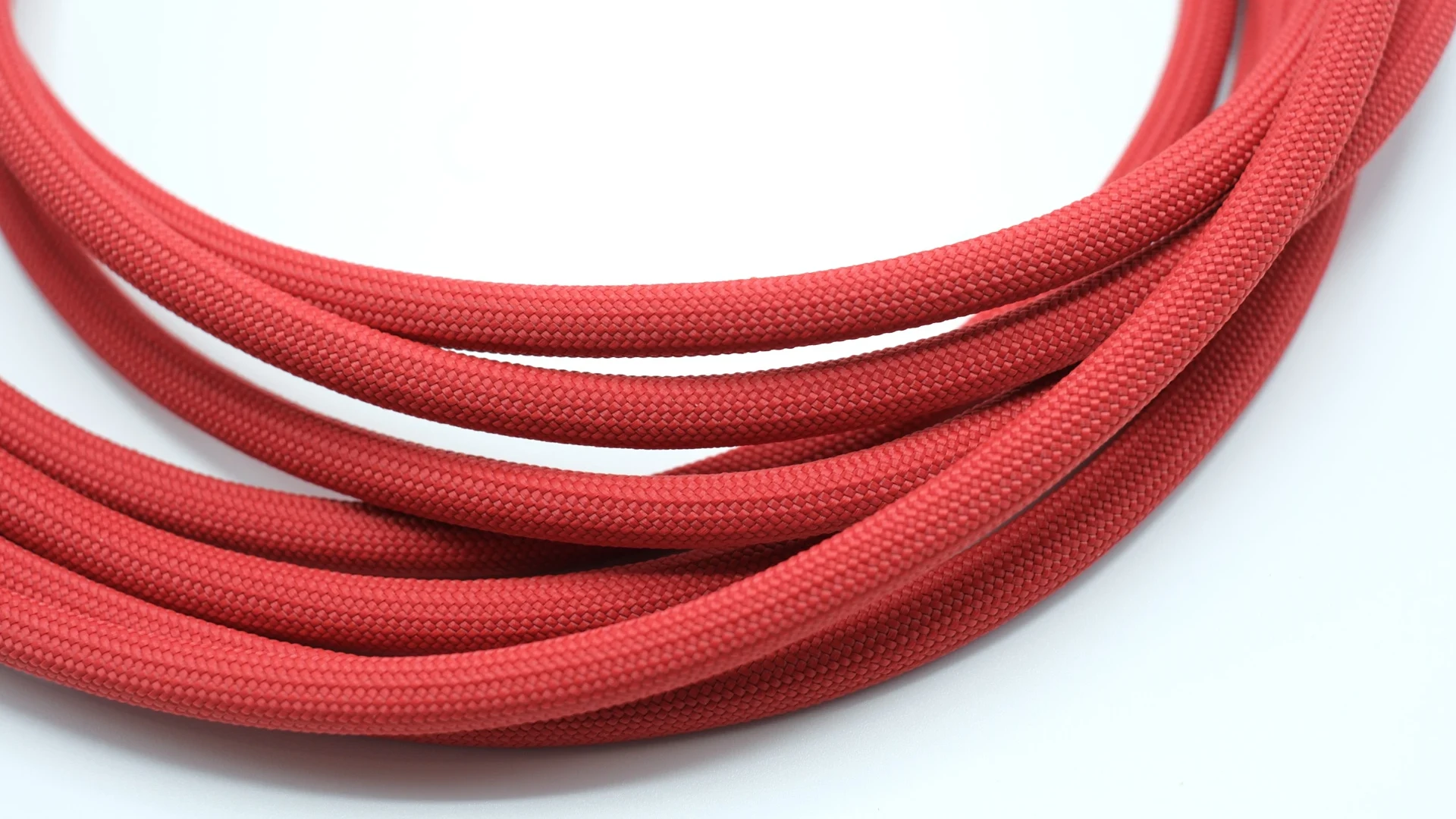 Close-up of a red braided cable coiled on a white surface.