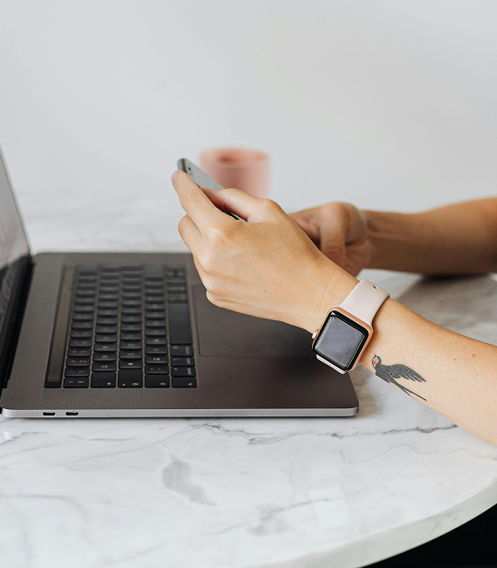 main de femme sur telephone et ordinateur