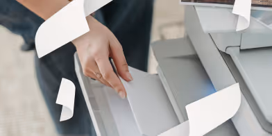 une main qui récupère du papier d'une imprimante