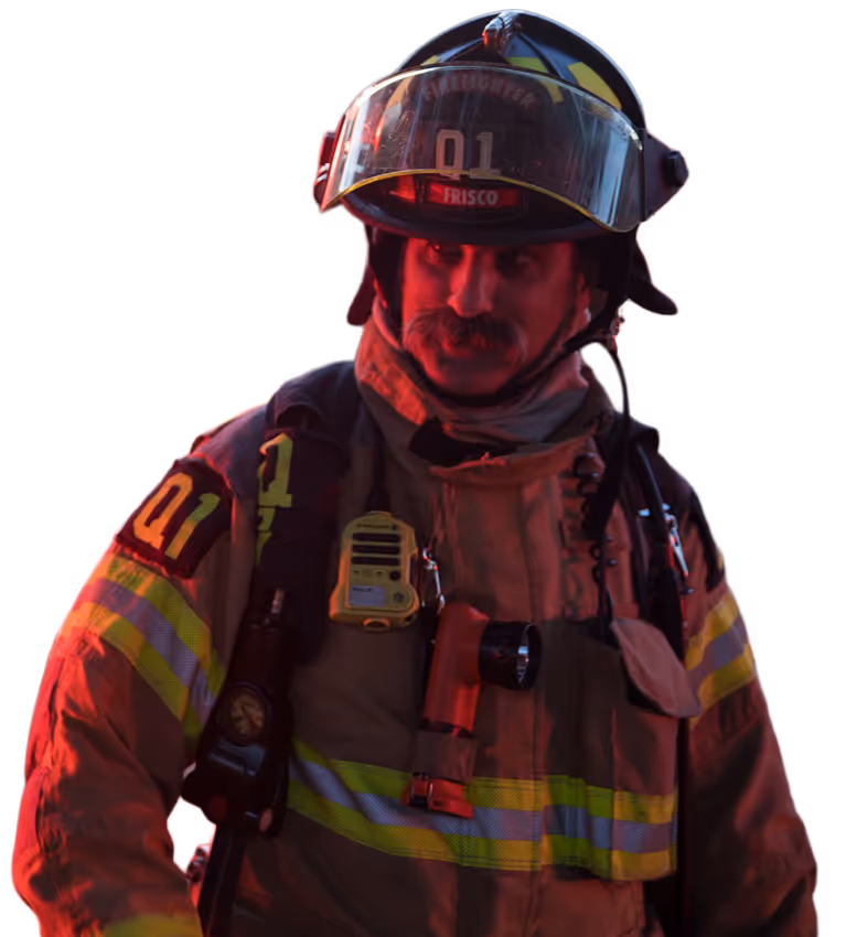 Frisco firefighter in full gear illuminated by emergency lighting