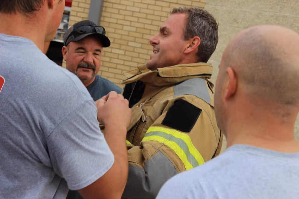 Frisco firefighter smiling and talking with team members outside a fire station during a training or community event