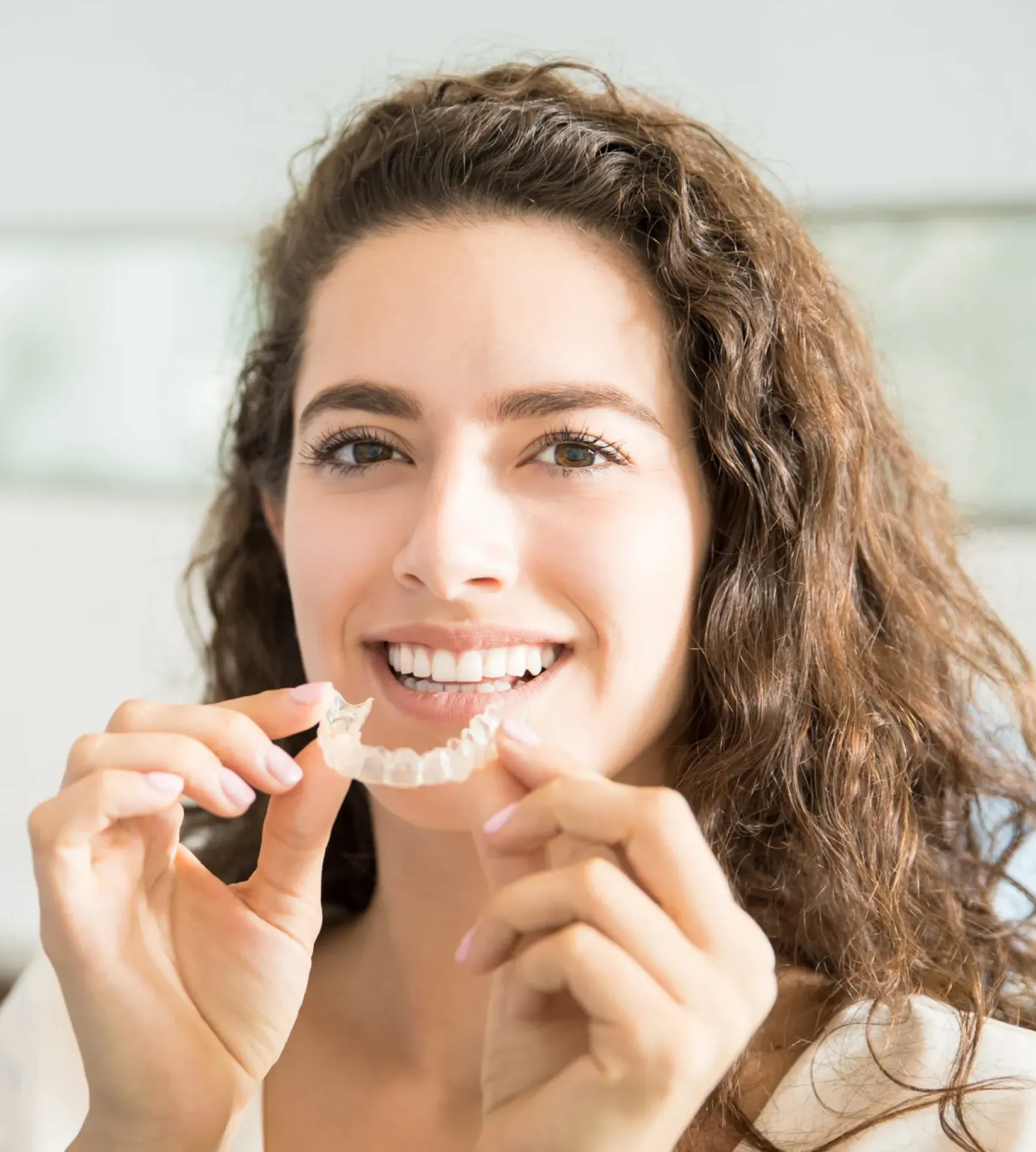 A woman is smiling while brushing her teeth.