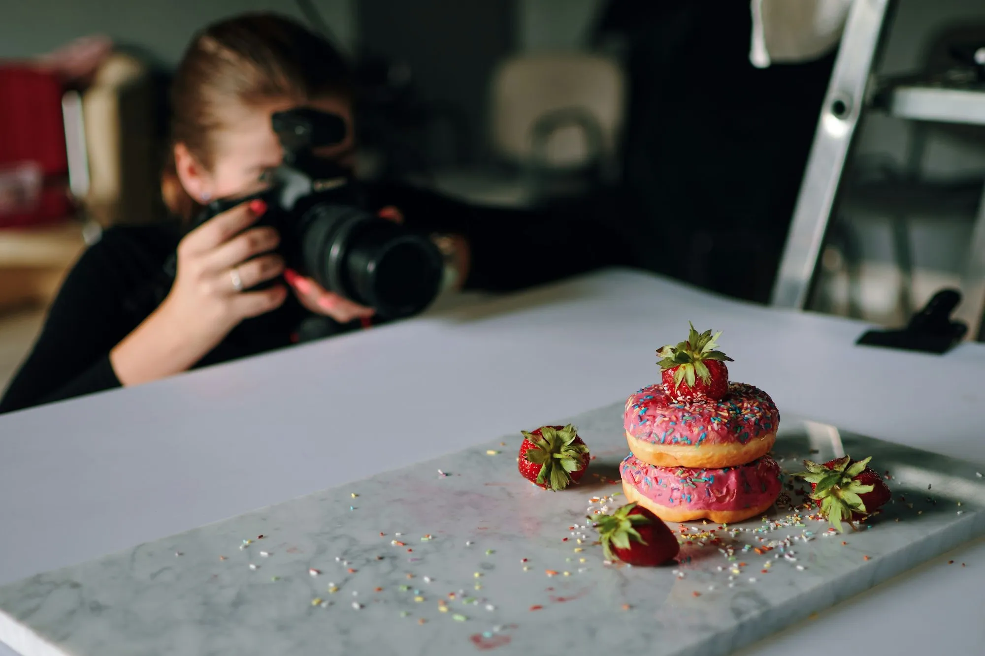 a woman taking the picture of a pastry using a digital camera.
