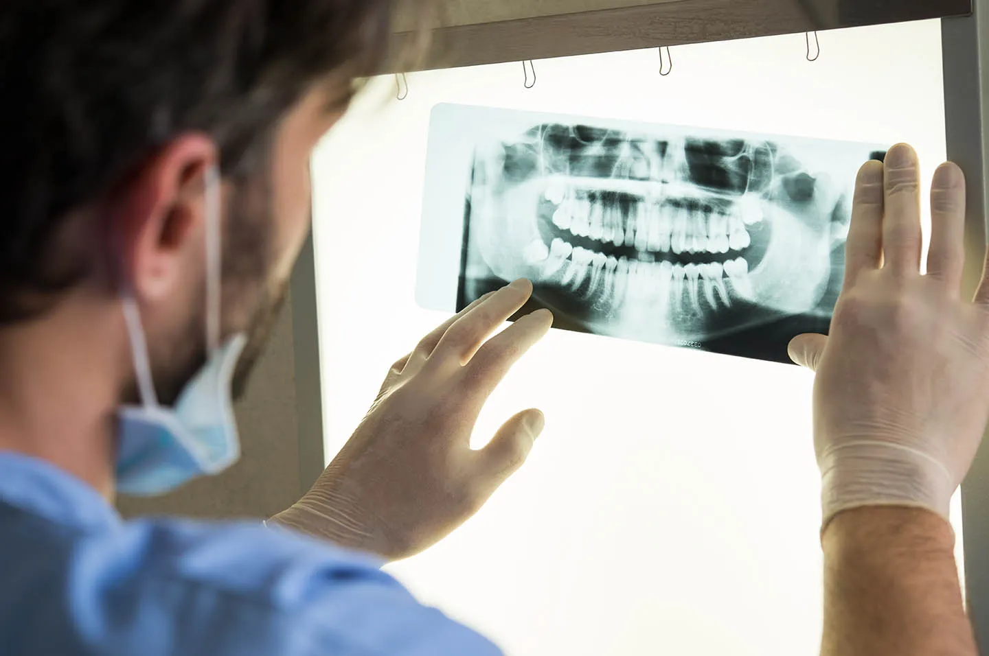 A man wearing a face mask looking at a picture of a tooth.