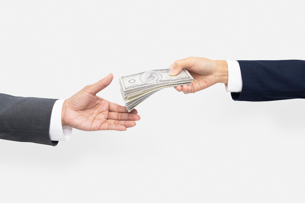 Two hands of which one hand giving money to other.