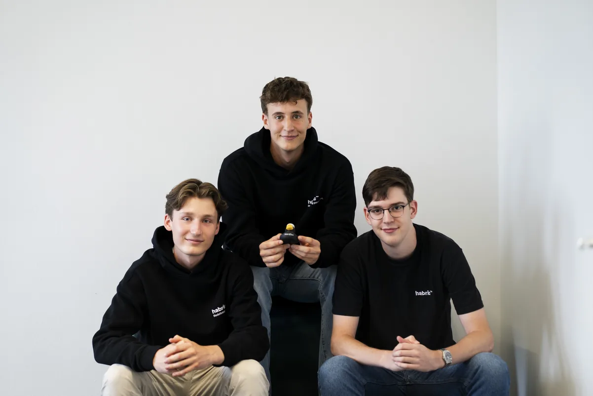 The three habric™ founders in front of a white wall, one holding a blind Sonar™ sensor