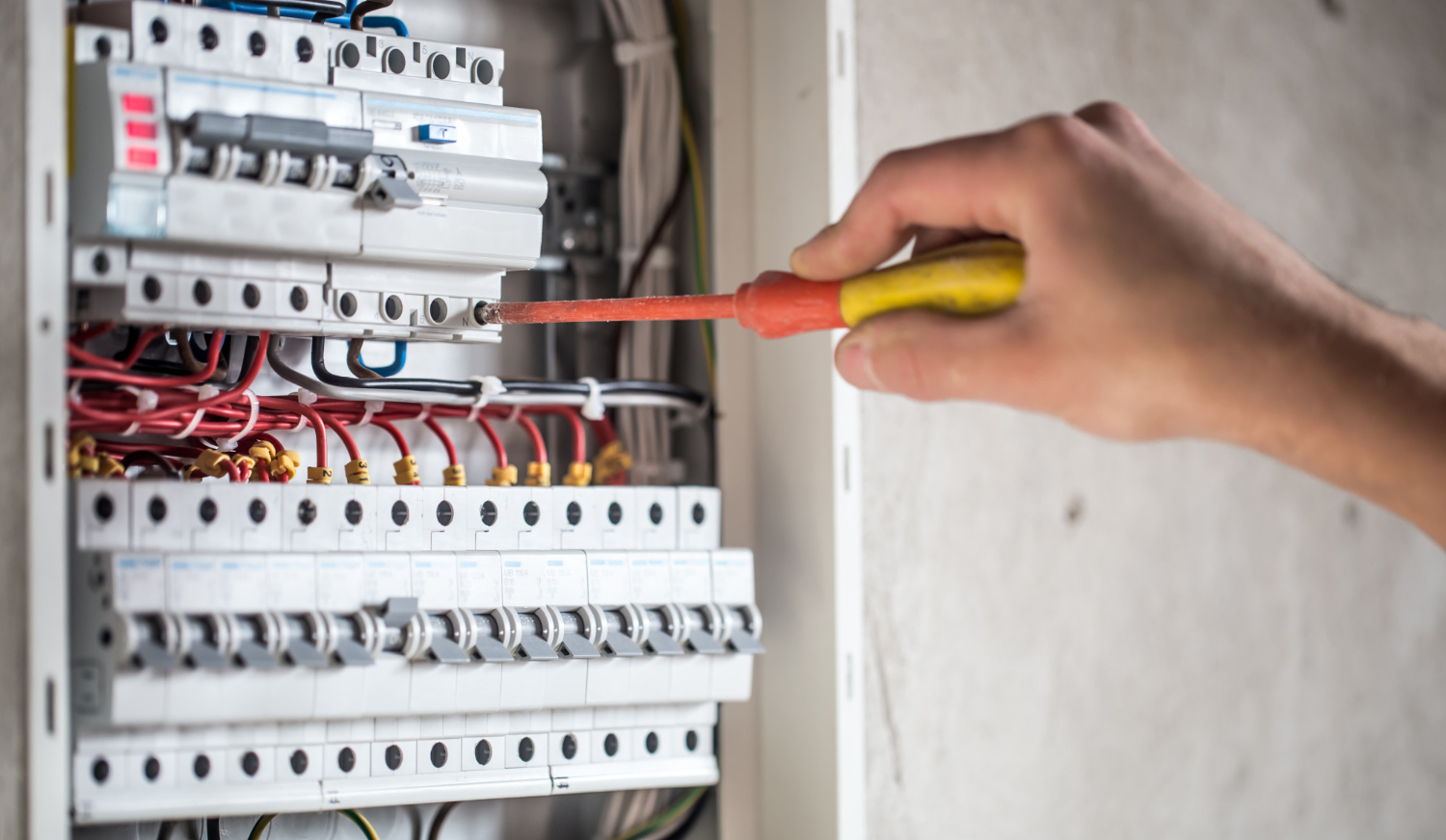 Hand using a screwdriver to work on an electrical panel, showcasing electrical installation services in Minneapolis, MN by Stafford Home Service Inc.