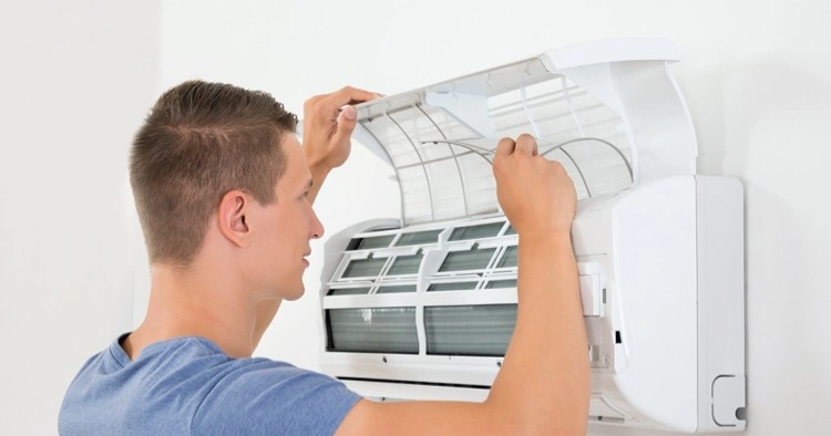 Man checking filter in mini-split AC.