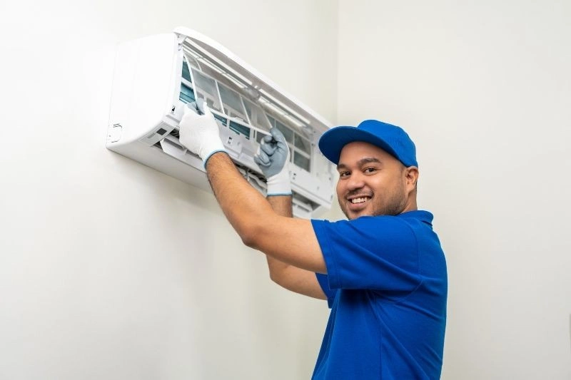 Technician services a mini-split AC.