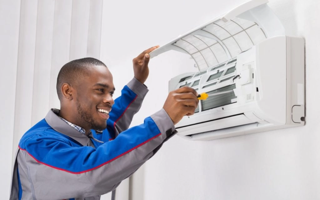 Smiling technician servicing a mini-split AC.