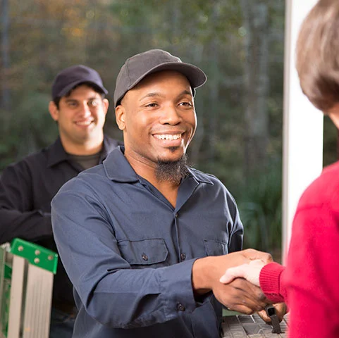 HVAC technician shaking hands with a homeowner, showcasing professional service and customer interaction in residential electrical services.