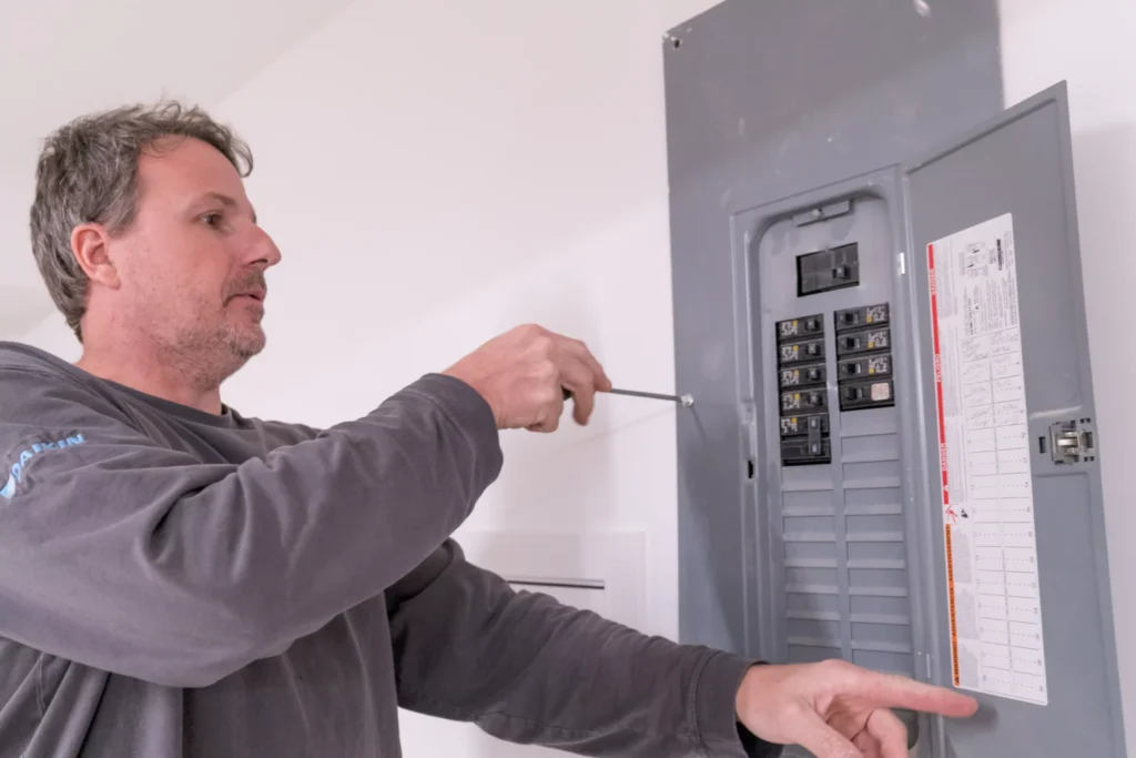 Electrician servicing a residential electrical panel in Minneapolis, MN, demonstrating expertise in electrical upgrades and maintenance.