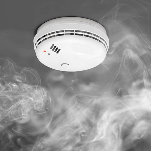 Smoke detector in a smoky environment, emphasizing home safety and fire prevention, relevant to smoke and carbon monoxide detector installation services in Minneapolis, MN.