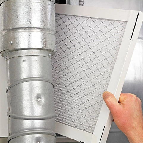 Hand inserting an air filter into a duct, illustrating air purification for improved indoor air quality and allergen reduction.
