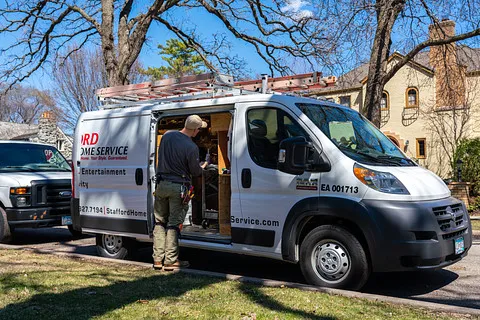 Stafford Home Service van parked on a residential street, technician preparing tools for heating and cooling service, emphasizing furnace installation and repair expertise in Minneapolis, MN.