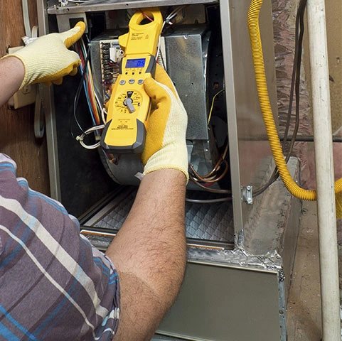 Technician using a multimeter to diagnose furnace issues during repair service in Minneapolis, emphasizing professional heating solutions.
