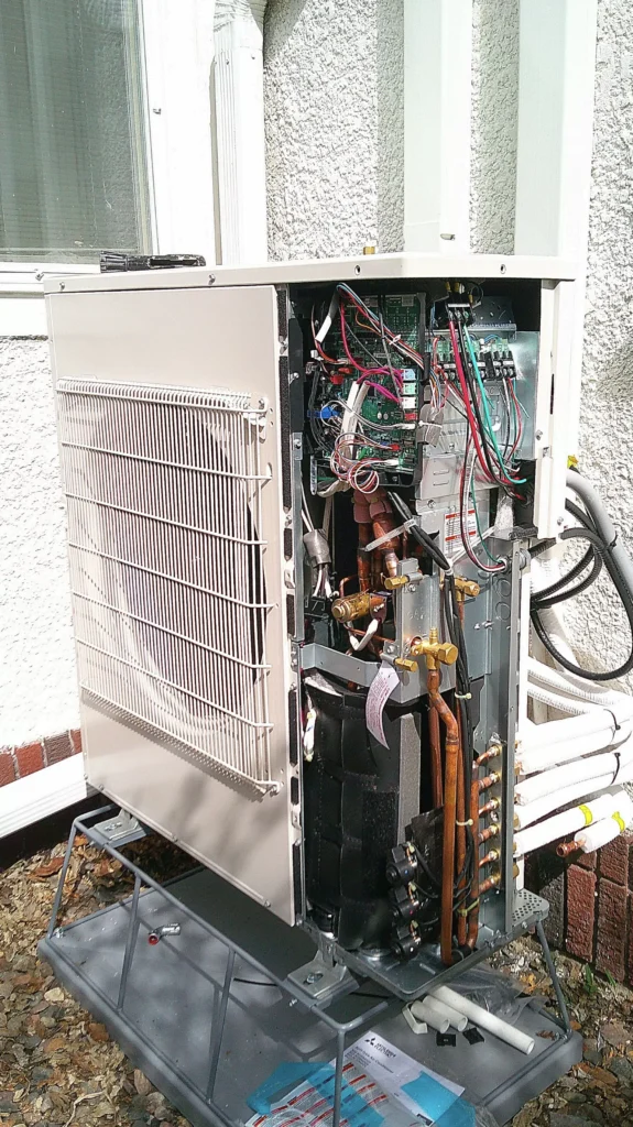 Close-up of a heat pump unit showing internal components, electrical wiring, and copper piping, relevant to HVAC installation services in Minneapolis, MN.