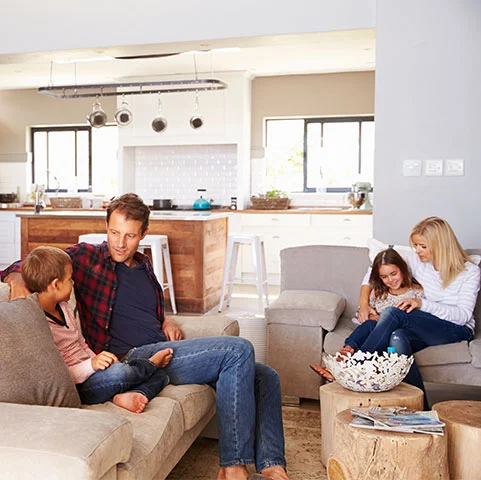 Family enjoying time together in a cozy living room with comfortable seating, emphasizing indoor comfort and home environment related to heating and cooling solutions.