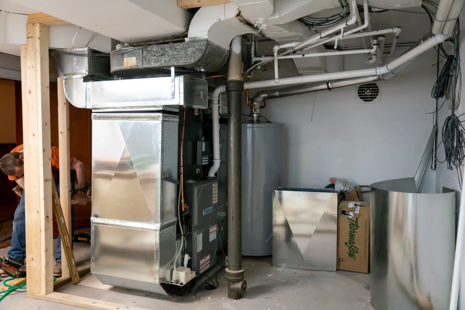 Furnace installation in a basement with ductwork and plumbing, showcasing HVAC system setup for heating repair services in Minneapolis, MN.