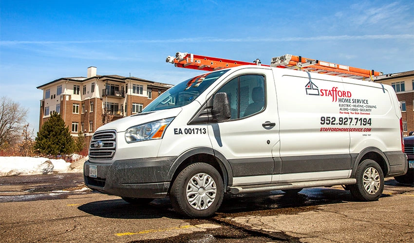 Stafford Home Service HVAC service van parked in front of residential building, featuring company logo and contact information, representing trusted heating and cooling solutions in Minneapolis, MN.