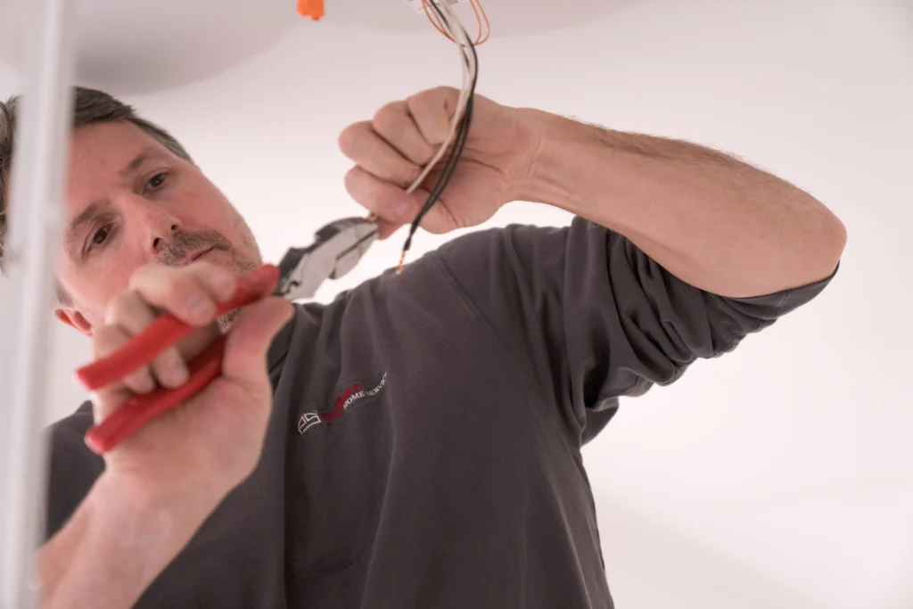 Electrician using pliers to work on electrical wiring, emphasizing residential electrical services and installations in Osseo, MN.
