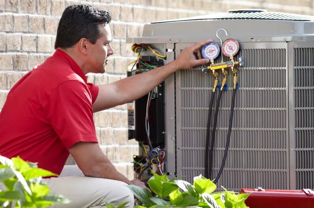 Technician checking refrigerant pressure on AC.