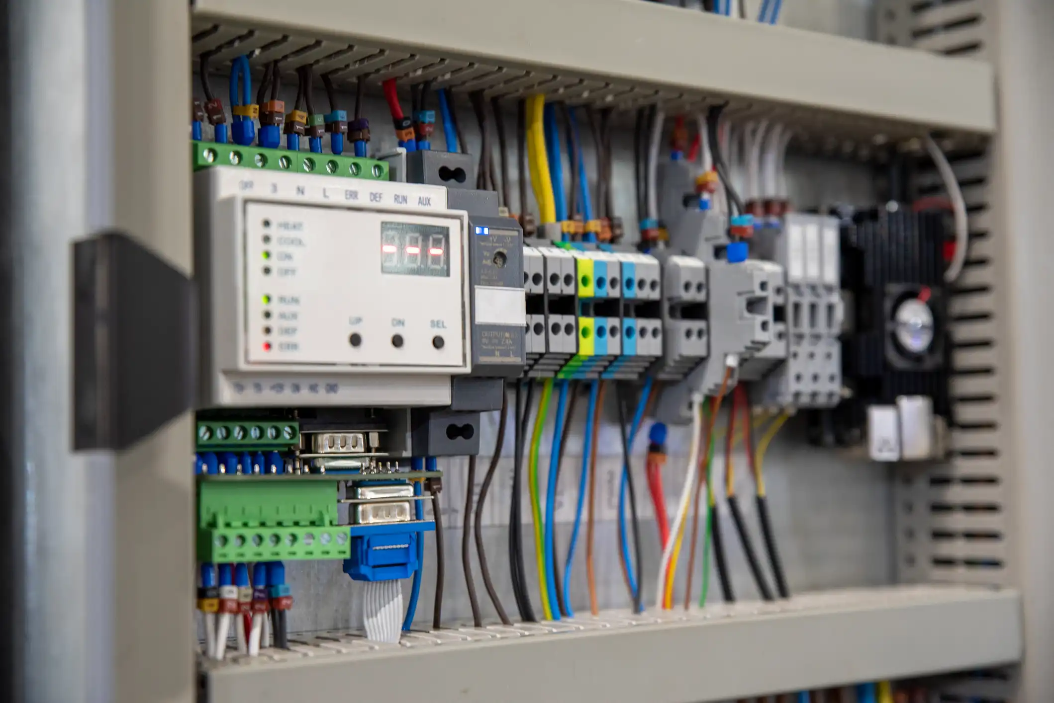 Close-up of a neatly wired electrical panel with multiple components, terminals, and a digital display module.