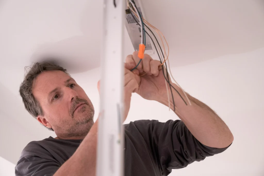 Electrician working on residential electrical wiring installation, focusing on safety and efficiency in home electrical systems.