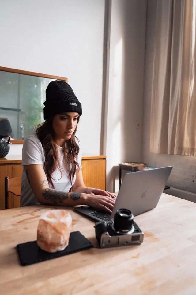 A woman sitting at a table using a laptop computer.