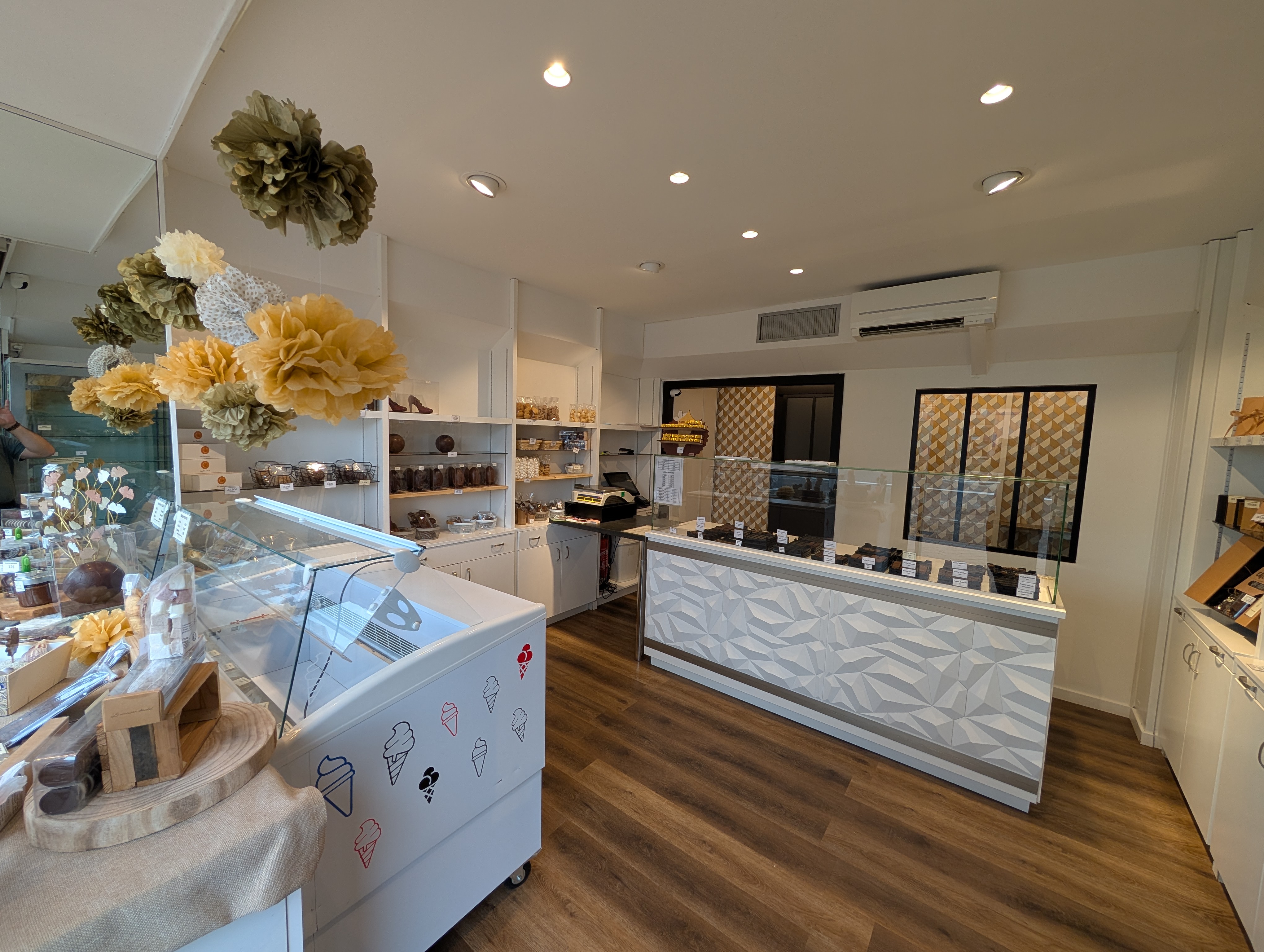 Intérieur moderne de la chocolaterie artisanale de la Maison Charrier à Dombasle-sur-Meurthe, avec comptoir et étagères garnies de créations en chocolat.