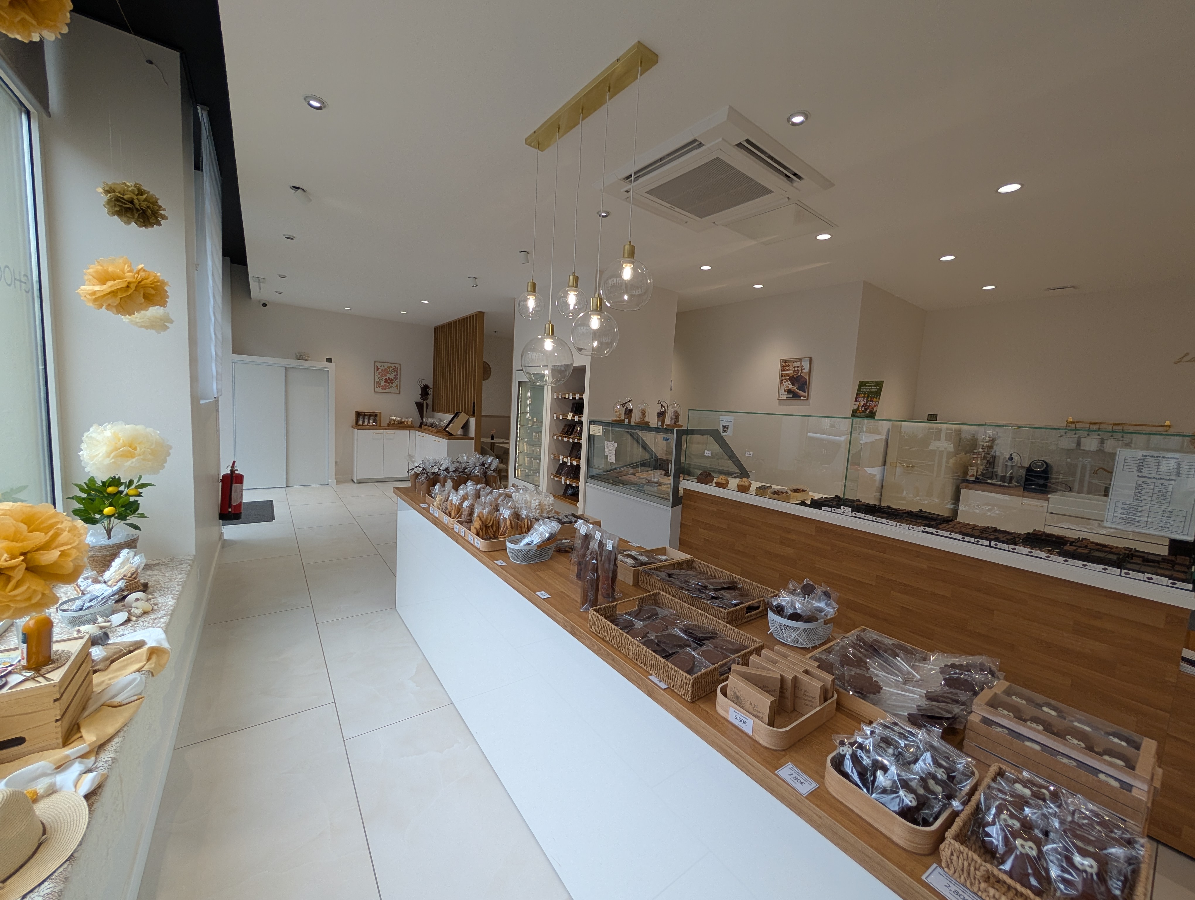 Intérieur moderne et chaleureux de la chocolaterie artisanale Maison Charrier à Lunéville, avec présentoirs garnis de créations en chocolat.