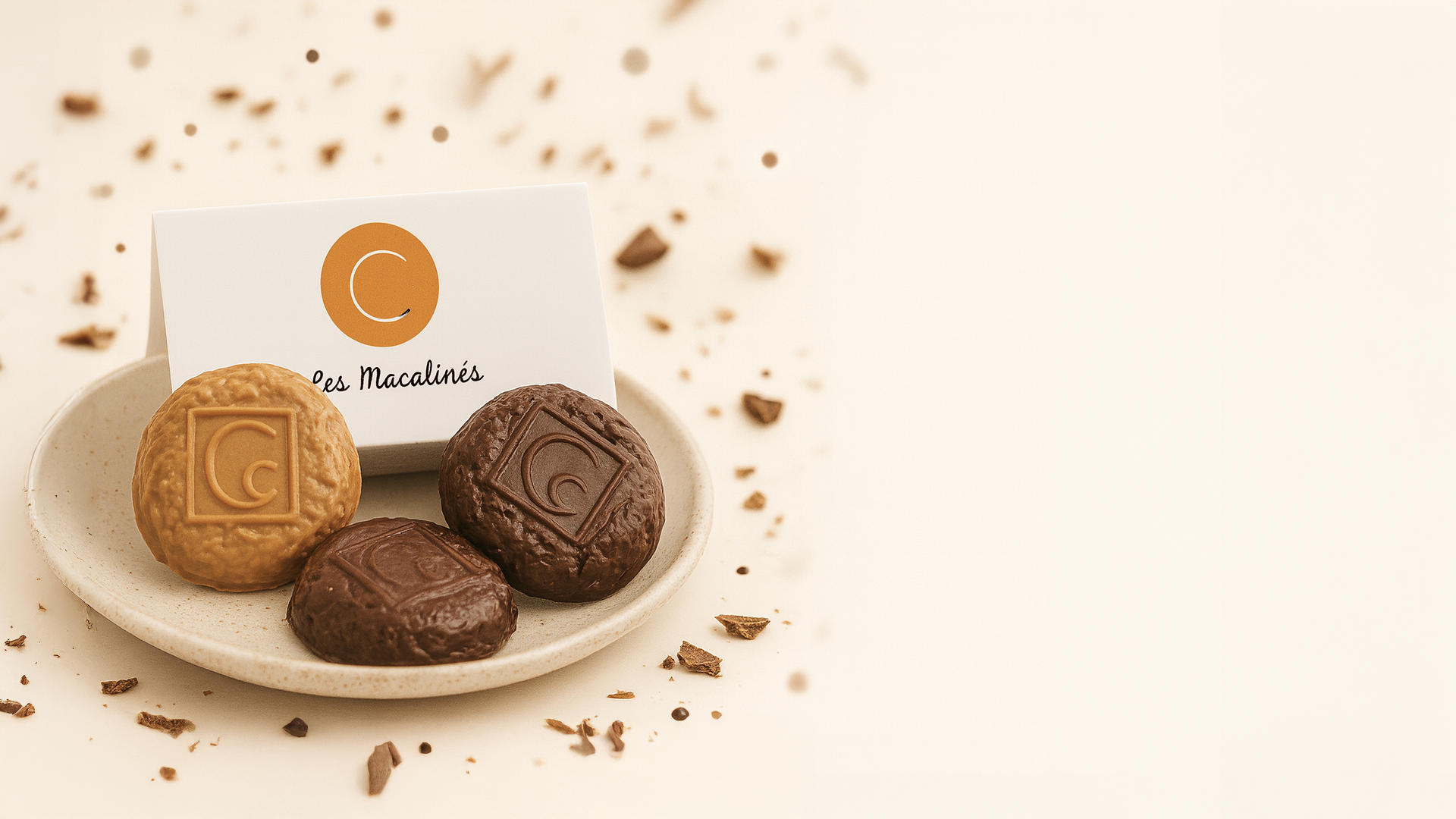 Macalinés, spécialité emblématique de la Maison Charrier, présentés sur un fond gourmand avec des éclats de chocolat.