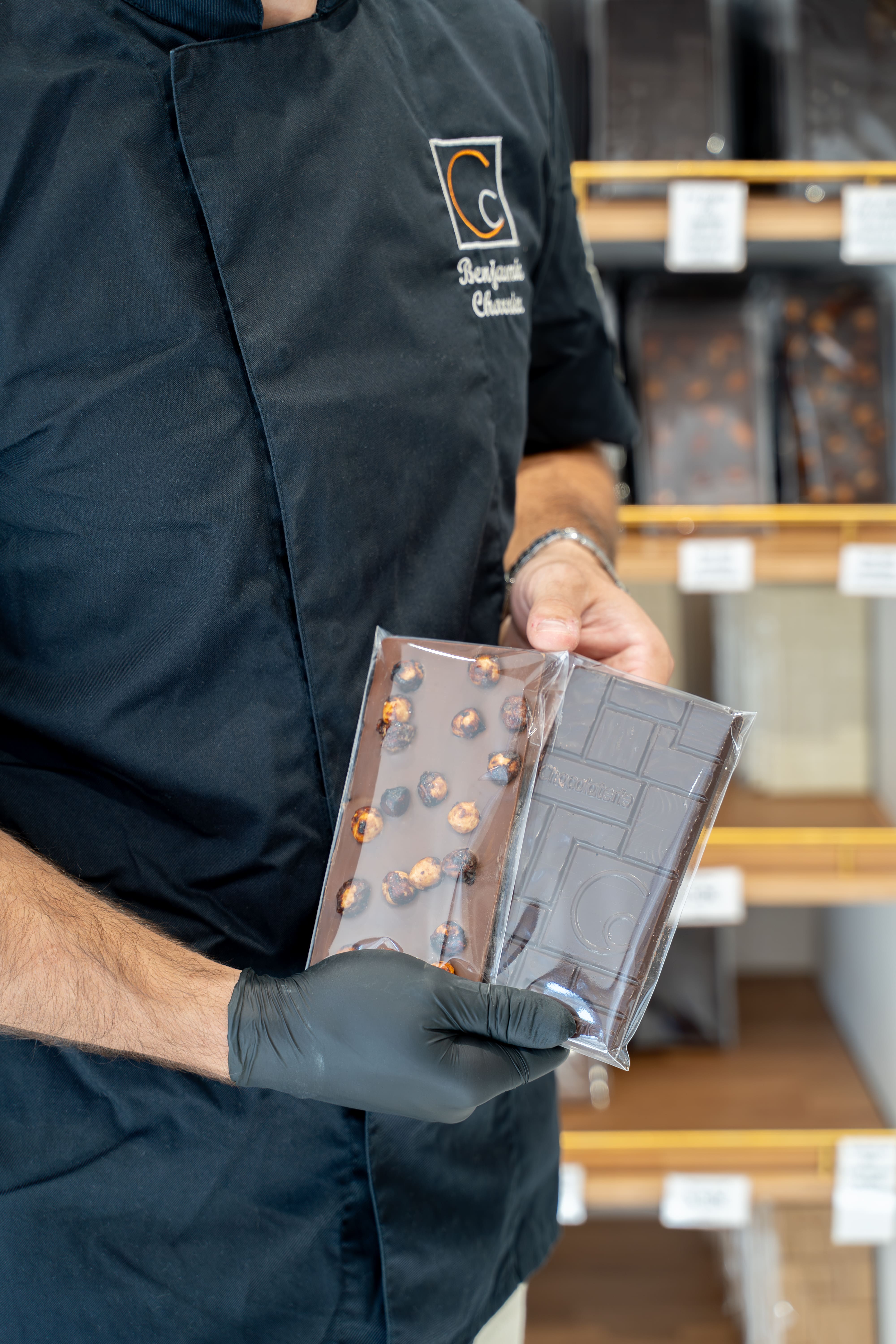 Benjamin Charrier, Maître chocolatier de la Maison Charrier, présentant une tablette de chocolat noir aux noisettes artisanale.