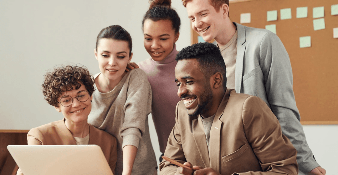 A group of people looking at a laptop.